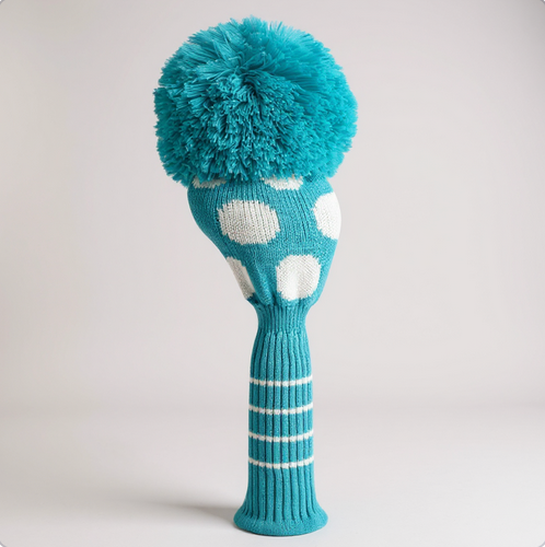Teal golf club head cover with white polka dots and pom-pom on a light gray background